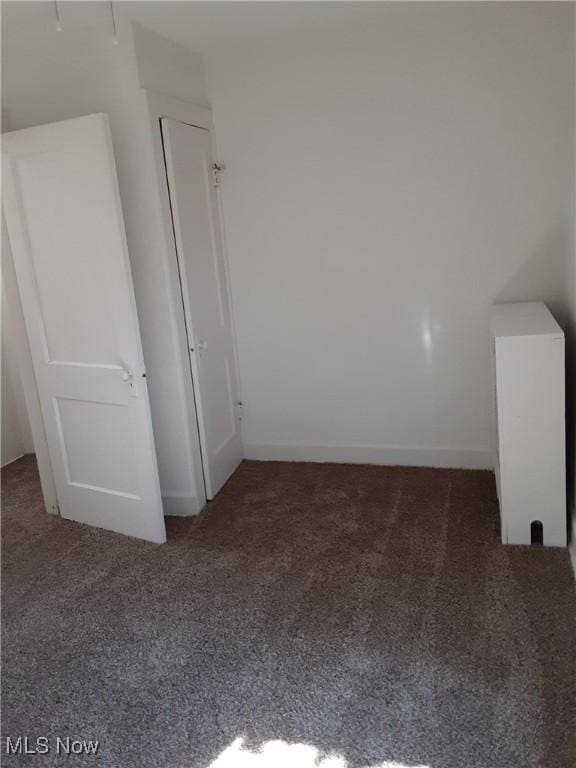 unfurnished bedroom with dark colored carpet