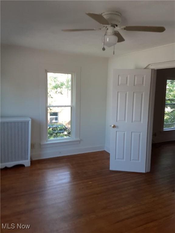 unfurnished bedroom featuring ceiling fan, dark hardwood / wood-style flooring, and radiator heating unit