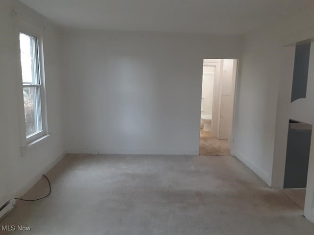 empty room featuring light colored carpet and a baseboard heating unit