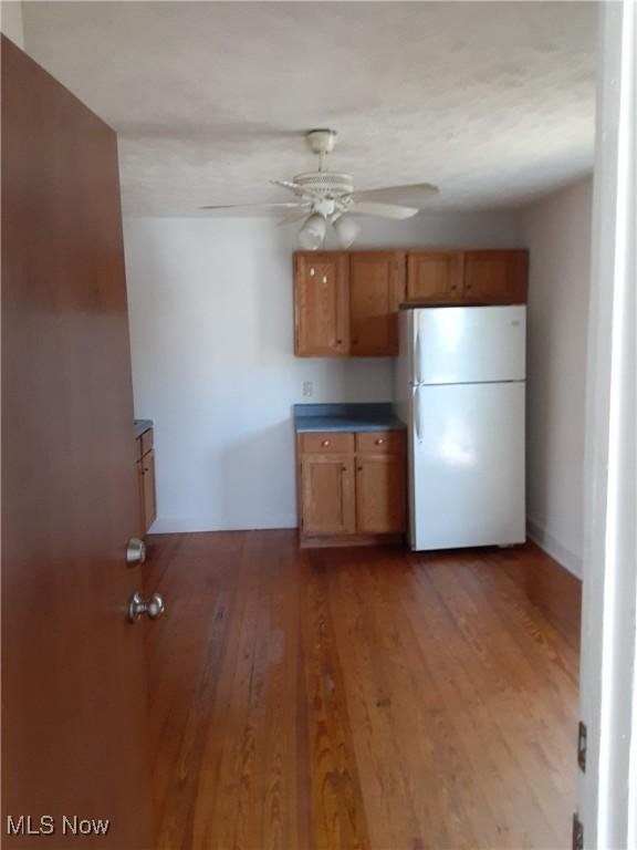 kitchen featuring hardwood / wood-style flooring, ceiling fan, and white fridge