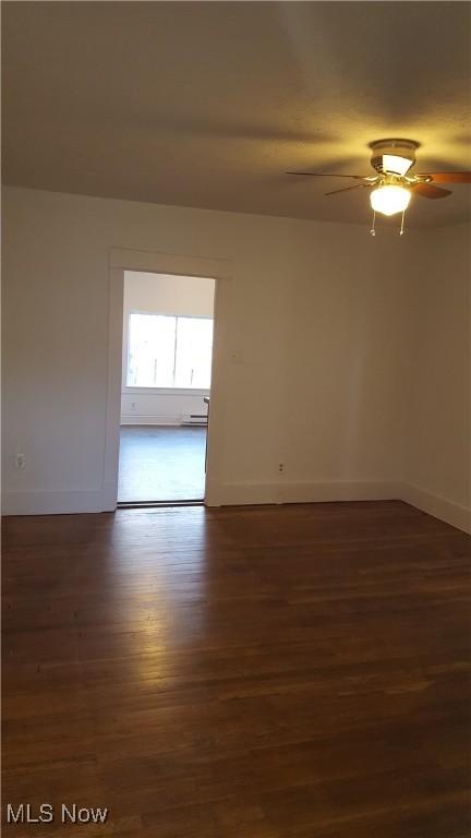 empty room with ceiling fan and dark hardwood / wood-style flooring