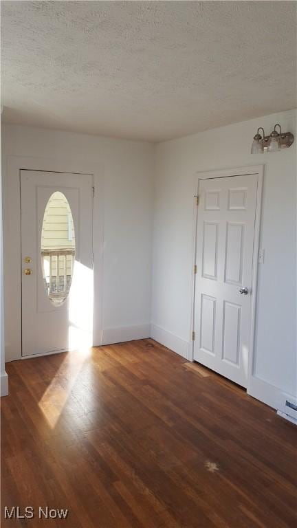 spare room featuring dark wood-type flooring and a textured ceiling