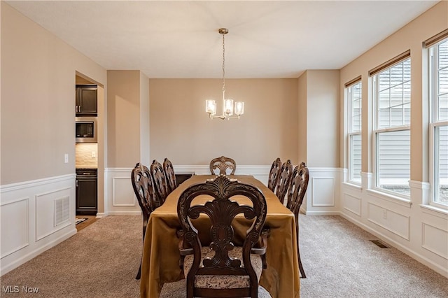 dining space with a chandelier, light colored carpet, and plenty of natural light