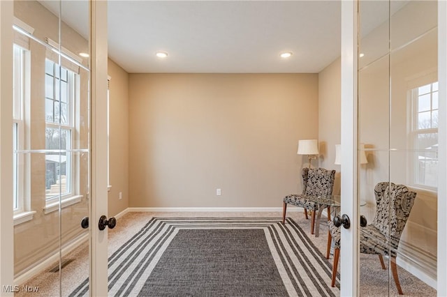 living area with carpet flooring, plenty of natural light, and french doors