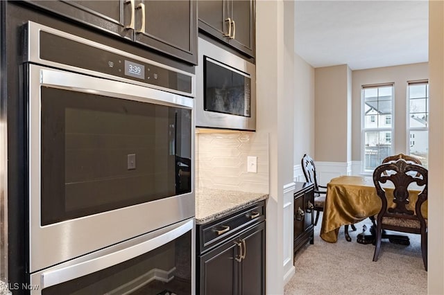 kitchen with decorative backsplash, stainless steel microwave, and light stone counters