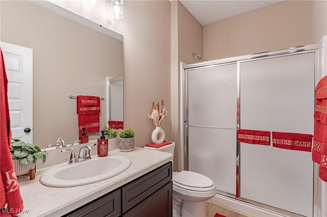 bathroom with a shower with door, vanity, and toilet