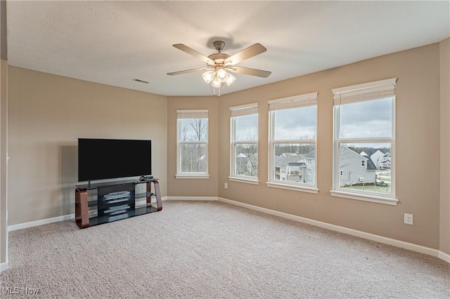 living room featuring carpet flooring, ceiling fan, plenty of natural light, and a textured ceiling