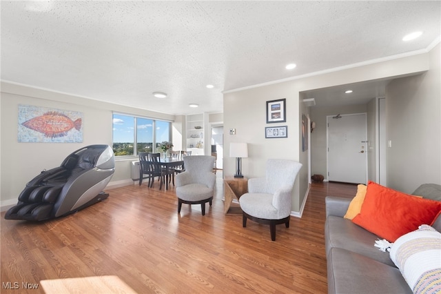 living room with hardwood / wood-style floors, built in shelves, crown molding, and a textured ceiling