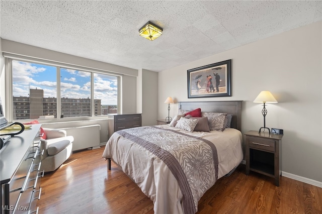 bedroom featuring dark hardwood / wood-style floors, radiator heating unit, and a textured ceiling