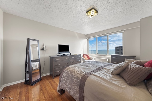 bedroom with hardwood / wood-style floors and a textured ceiling