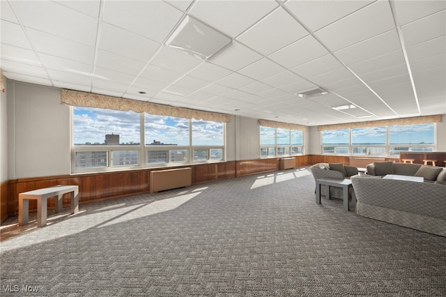 unfurnished living room with carpet, a paneled ceiling, and radiator