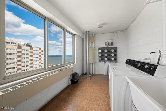 clothes washing area featuring radiator heating unit, sink, a water view, and washing machine and clothes dryer