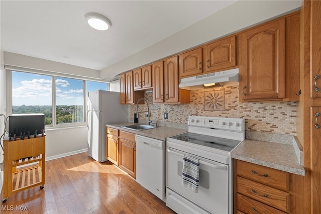 kitchen with white appliances, tasteful backsplash, light hardwood / wood-style flooring, and sink