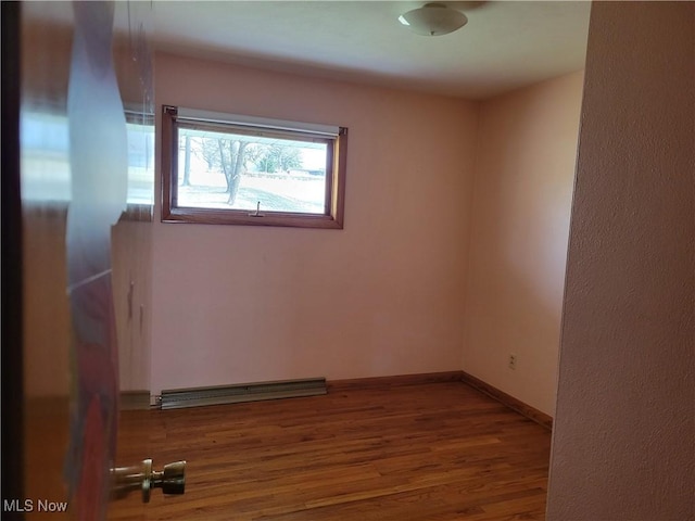 spare room with a baseboard radiator and wood-type flooring