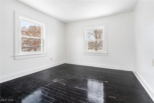 spare room with a wealth of natural light and dark wood-type flooring