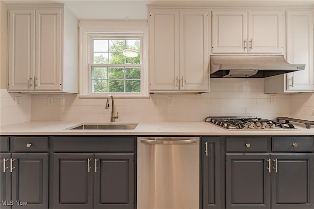 kitchen with light stone countertops, tasteful backsplash, stainless steel appliances, sink, and white cabinets