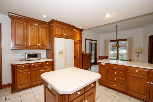 kitchen with white refrigerator with ice dispenser, pendant lighting, light tile patterned floors, and a kitchen island