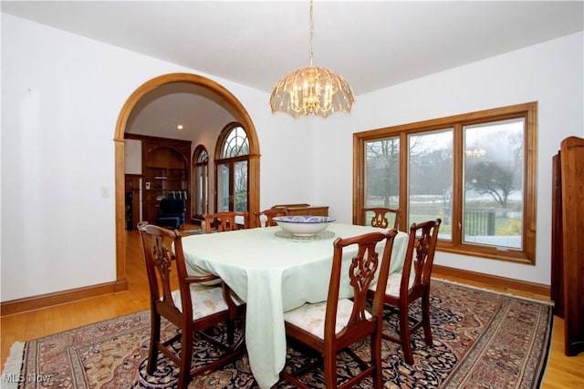 dining space with light hardwood / wood-style floors and an inviting chandelier