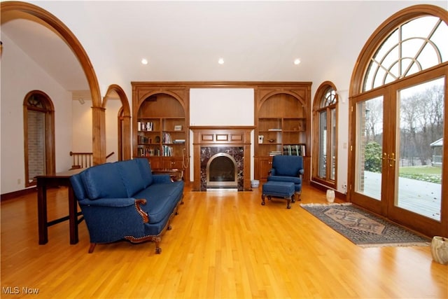 sitting room with a fireplace, french doors, light hardwood / wood-style flooring, and built in shelves