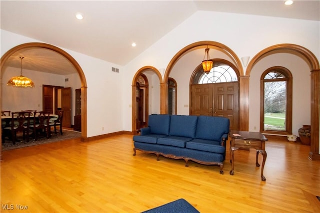 living room with a chandelier, vaulted ceiling, and light wood-type flooring