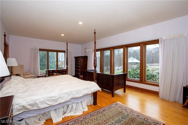 bedroom with multiple windows and light hardwood / wood-style flooring