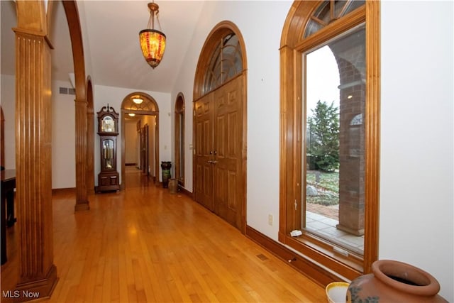 hallway featuring vaulted ceiling, decorative columns, and light hardwood / wood-style flooring