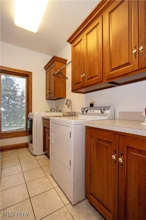 clothes washing area featuring light tile patterned flooring, cabinets, and washing machine and clothes dryer