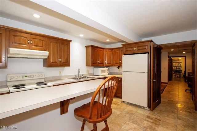 kitchen with a kitchen bar, white appliances, and sink