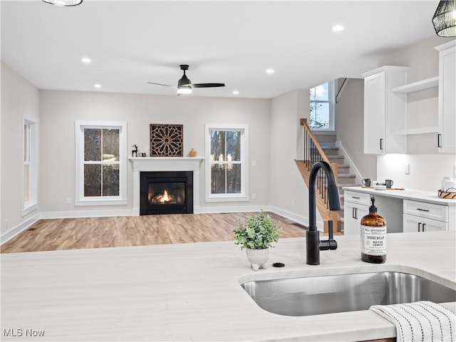 kitchen with light hardwood / wood-style flooring, white cabinetry, ceiling fan, and sink