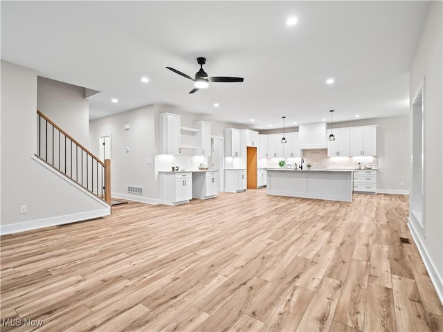 unfurnished living room featuring ceiling fan and light hardwood / wood-style flooring