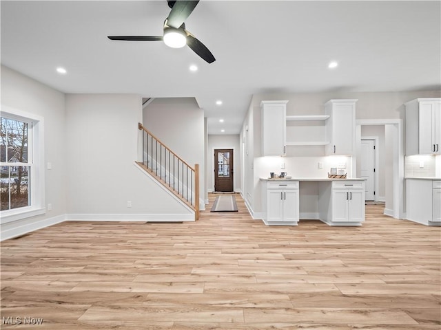 kitchen featuring white cabinets, ceiling fan, light wood-type flooring, and tasteful backsplash