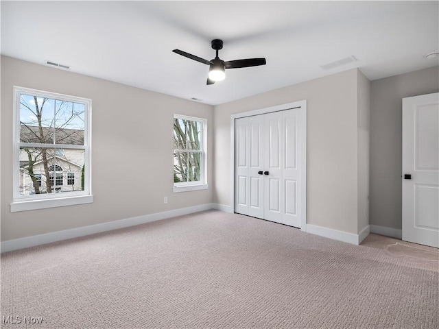 unfurnished bedroom featuring ceiling fan, a closet, and light colored carpet