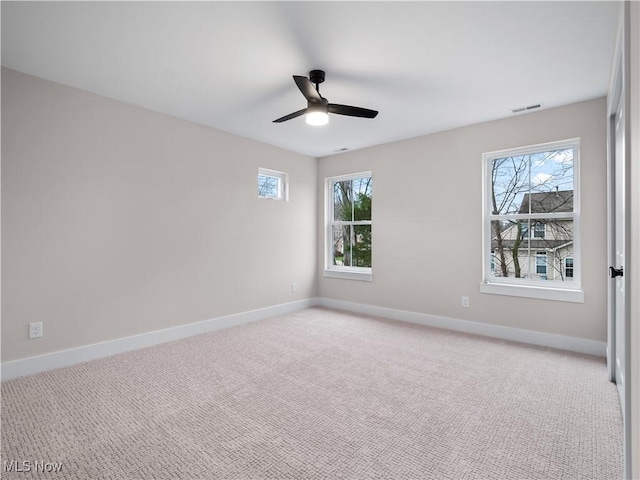 empty room with light colored carpet, a wealth of natural light, and ceiling fan