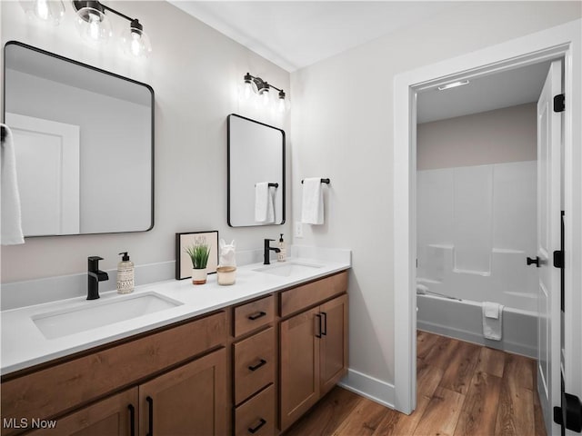 bathroom featuring hardwood / wood-style flooring, vanity, and shower / washtub combination