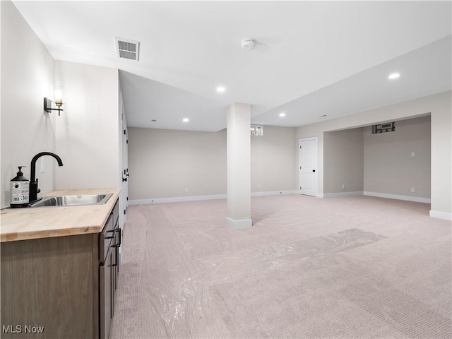 basement with sink and light colored carpet