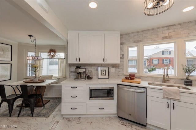 kitchen with pendant lighting, white cabinetry, sink, and stainless steel appliances