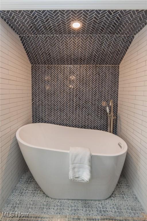 bathroom with a bathing tub and brick wall