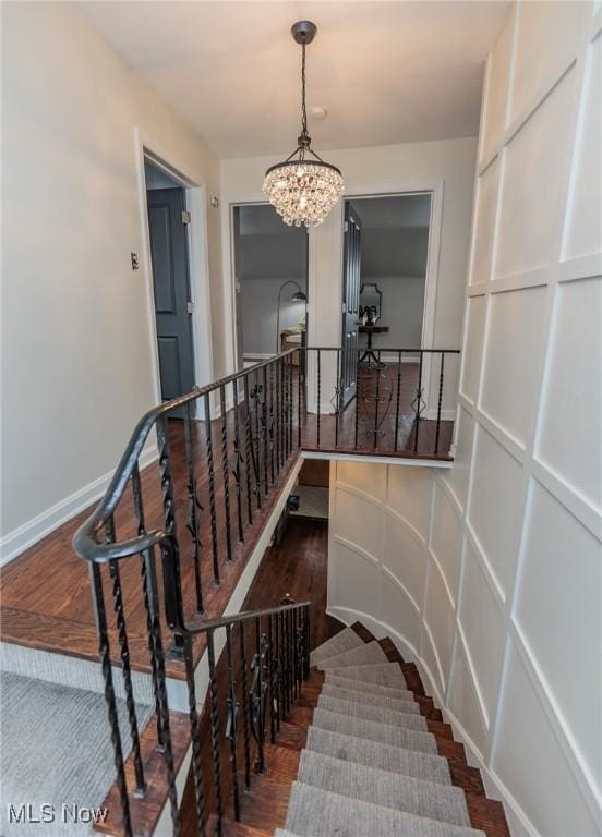 staircase with wood-type flooring and a chandelier