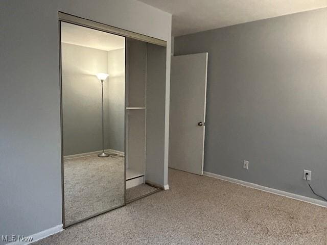 unfurnished bedroom featuring light carpet and a closet