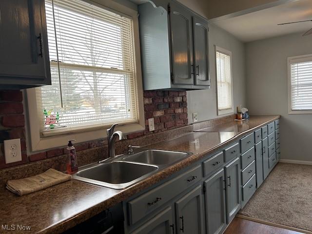 kitchen with ceiling fan, carpet flooring, sink, and gray cabinetry