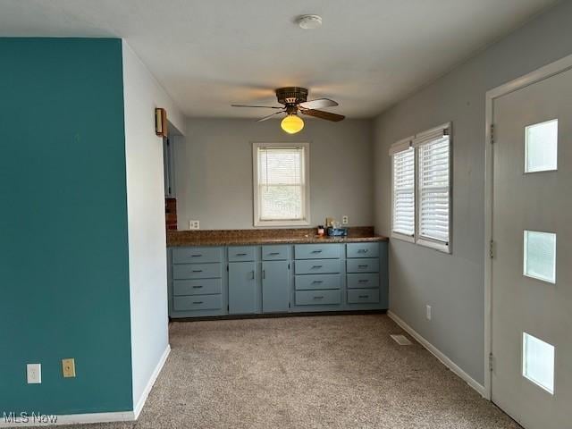 kitchen featuring gray cabinetry, light colored carpet, and ceiling fan