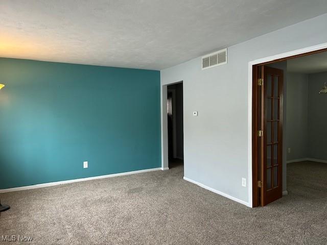 carpeted empty room with a textured ceiling