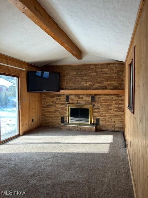 unfurnished living room featuring carpet floors, lofted ceiling with beams, wooden walls, and a textured ceiling