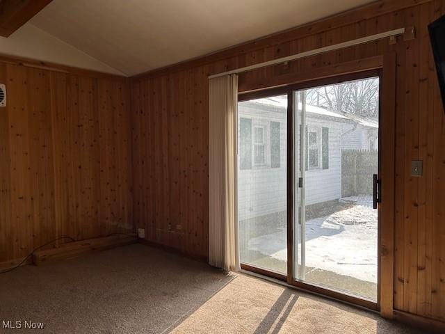 doorway featuring lofted ceiling with beams, carpet floors, and wooden walls