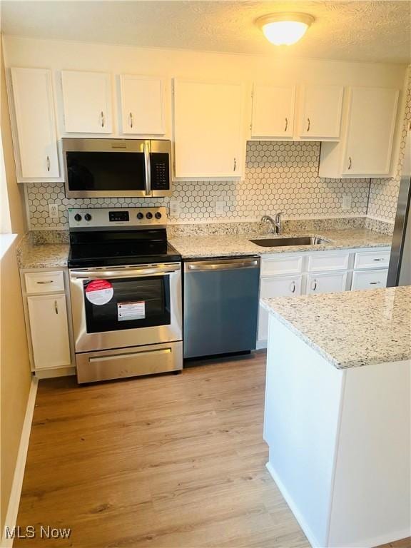 kitchen with sink, stainless steel appliances, light hardwood / wood-style flooring, backsplash, and white cabinets