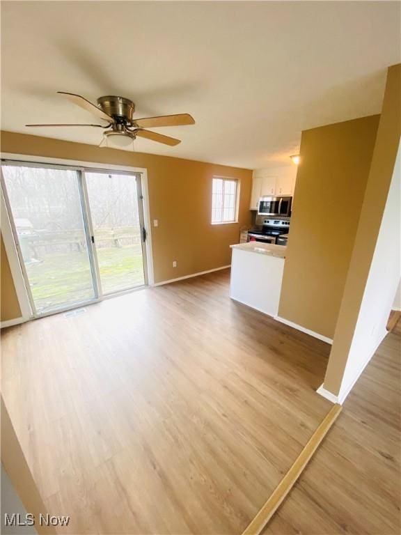 unfurnished living room with light hardwood / wood-style flooring, a wealth of natural light, and ceiling fan