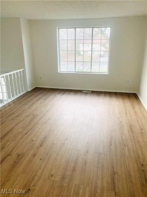 unfurnished room with a textured ceiling and light wood-type flooring