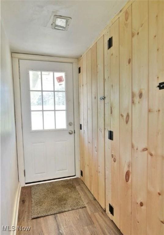 entryway with wooden walls and light hardwood / wood-style floors