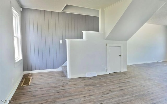 interior space featuring wooden walls, light hardwood / wood-style flooring, and ornamental molding