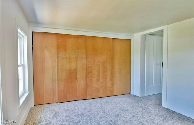 unfurnished bedroom with light carpet and a closet